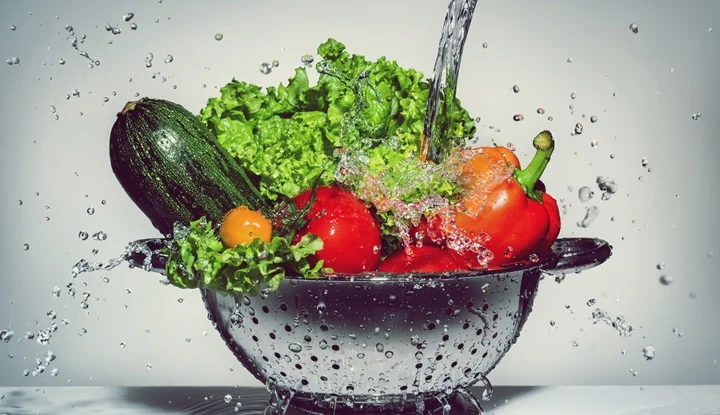 vegetables in a colander under running water