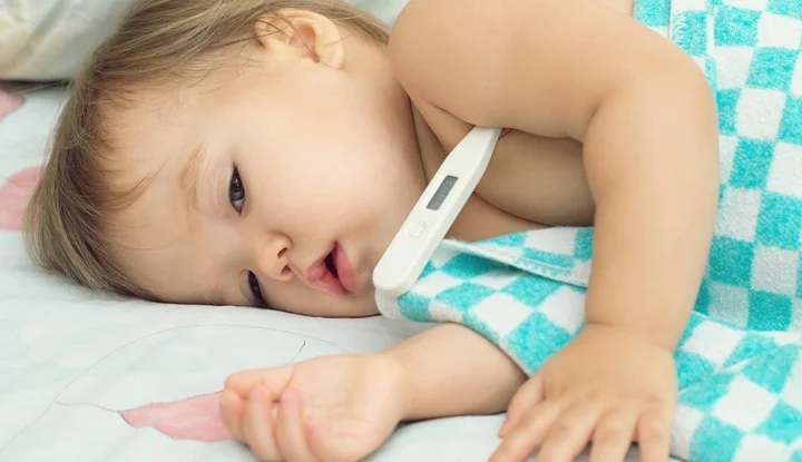 Baby ailing and lying with thermometer
