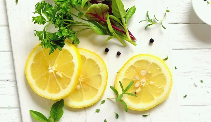 fresh garden herbs and lemon on a white surface