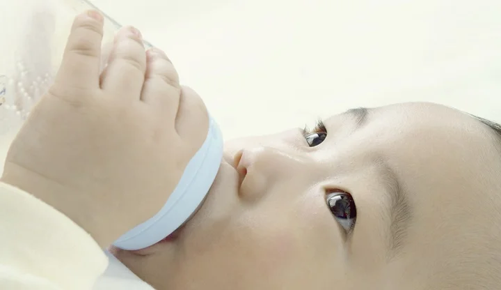 a baby sucking a nursing bottle