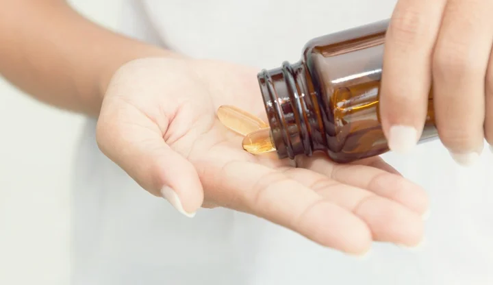 closeup hand holding fish oil vitamin for healthy