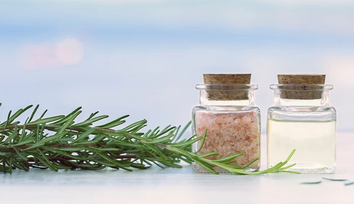 Rosemary aromatherapy essential oil and salt in bottles on sunset