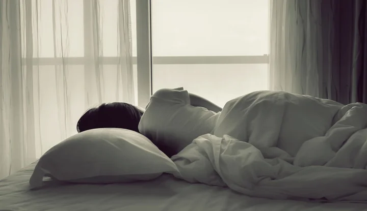 Young woman sleeping in bed beside the window