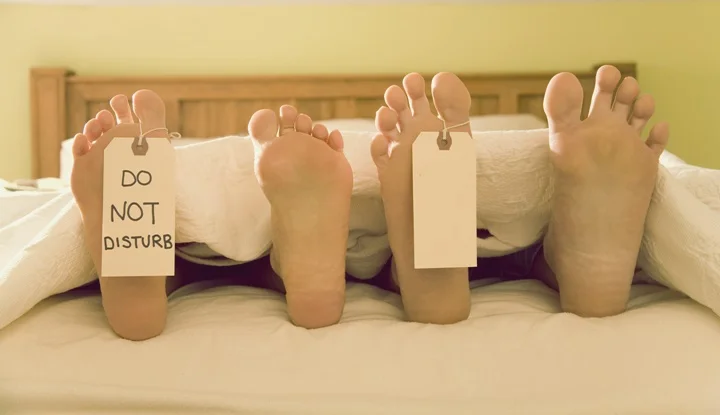 Couple?s bare feet with Do Not Disturb Til Noon signs