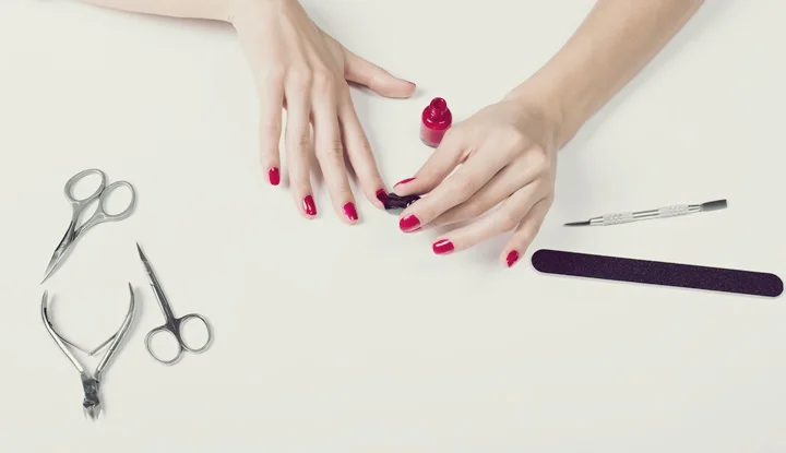 Female hand applied red lacquer on the nails