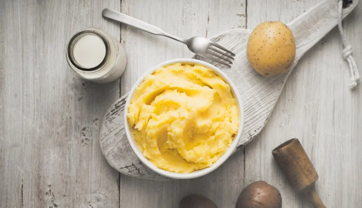 Mashed potatoes in the bowl on  white wooden table  vertical