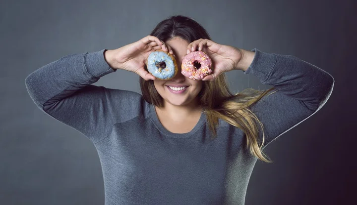 Happy beautiful young caucasian plus size model posing with donuts